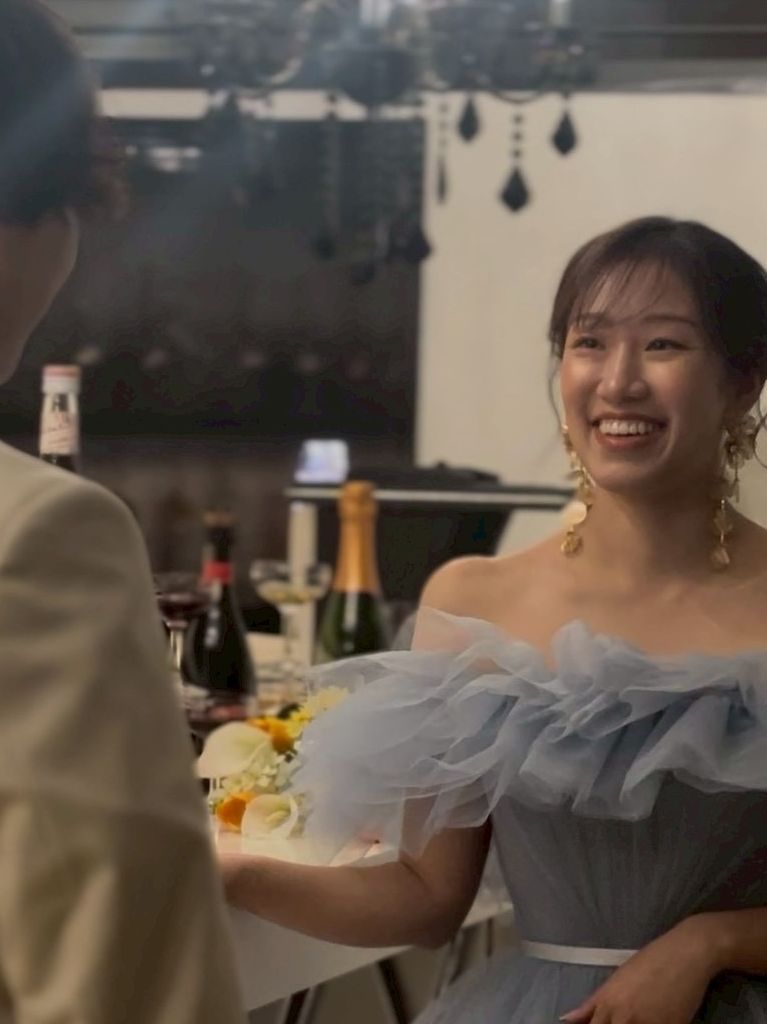 披露宴会場で淡いブルーのドレスを身に纏い新郎に向けて満面の笑みを浮かべる新婦のお顔。