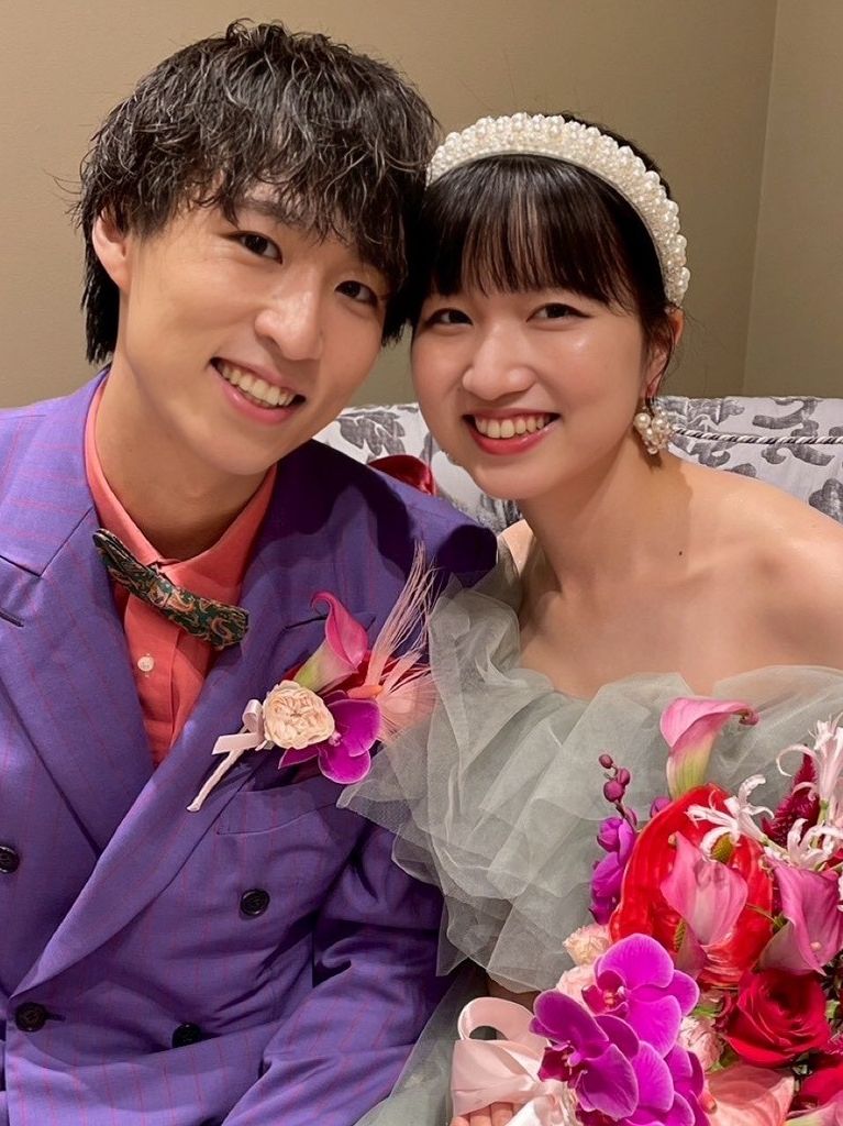 幸せそうな新郎新婦の自然な笑顔と華やかな装花が印象的なブライダルシーン